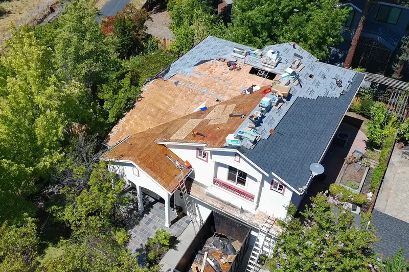 Aerial view of a two-story house during tear-off, with bare deck showing